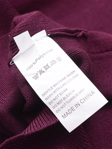 Détail macro de l'étiquette d'entretien et de taille sur un pull en maille côtelée bordeaux