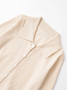 Dettaglio del cardigan in maglia beige con colletto polo e bottoni bianchi