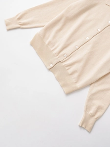 Dettaglio polo in maglia di cashmere beige con costine fini e bottoni rotondi