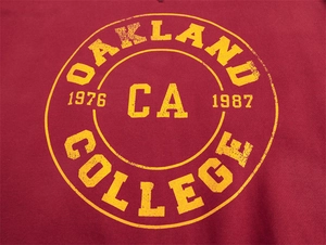 Dettaglio della stampa gialla Oakland College 1976 su felpa lavata in rosso scuro