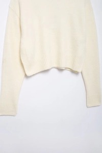 Vue détaillée de l'ourlet côtelé et de la texture en maille douce sur ce pull blanc crème