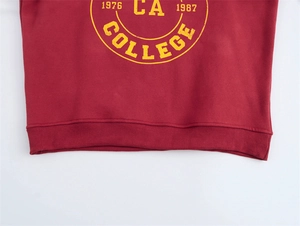 Dettaglio di felpa bordeaux con stampa college gialla vintage e orlo a costine fine