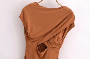Detail of caramel sleeveless dress featuring front cross-drape pleats and waist cutout design