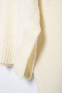 Détail des poignets côtelés sur un pull en maille douce de couleur crème pour femme
