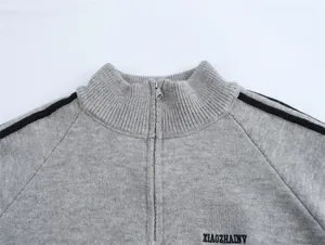 Détail du pull en maille gris avec col montant zippé et écusson brodé 1990 sur la poitrine