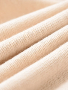 Primo piano del tessuto in maglia di cashmere beige con consistenza morbida e dettagli