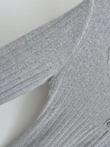 Détail macro du haut en maille côtelée grise avec dentelle pointelle et boutons assortis