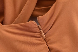 Detailed close-up of invisible zipper closure on caramel ruched slim fit dress