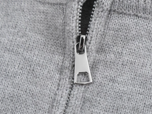 Détail de la fermeture éclair en métal argenté sur un pull en maille grise pour femme