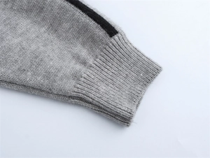 Gros plan d'une manche en tricot gris avec poignets côtelés et bande noire sportive