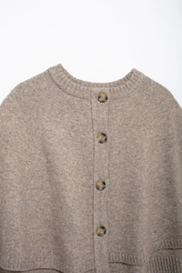 Detail of round neck ribbed collar and dark tortoiseshell buttons on knit cardigan