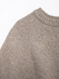 Detail of round neck ribbed collar and raglan sleeve seams on brownish knit sweater