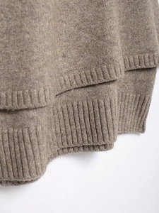 Close-up of the ribbed hem and textured knit fabric on a dark camel cardigan