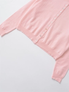 Close-up of pink knit cardigan with mother-of-pearl buttons and ribbed cuffs