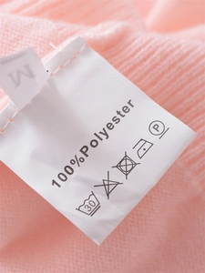 Detail view of the pink knit sweater showing the M size and 100% polyester care label
