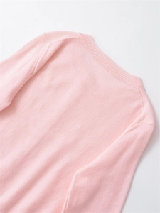 Close-up of pink knit top detailing the fine ribbed round neckline and soft texture