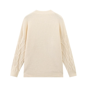 Detail der Stricktextur des cremefarbenen Pullovers mit Wabenmuster und Zopfstrickärmeln