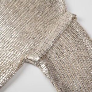 Gros plan sur la maille métallisée montrant la texture brillante du pull à manches longues