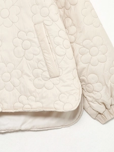 Detail der beige gesteppten Jacke mit Blumenmuster und glatter, seidenartiger Textur