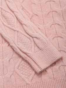 Detail eines rosa Zopfstrickpullovers mit Rippstrickbündchen und weicher Wollmischung