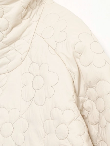 Nahaufnahme der floralen Steppung auf der weißen langärmeligen Winterjacke Damen