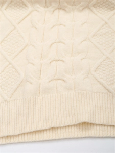 Nahaufnahme von cremefarbenem Strickpullover mit Zopfmuster und geripptem Saumdetail