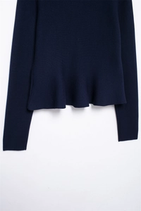 Detail of dark blue knit jacket featuring a feminine peplum hem and fine texture