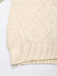 Nahaufnahme des cremefarbenen Strickpullovers mit Zopfmuster und Rautenstrukturen