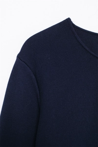Detailed view of the navy blue fine-knit sweater neckline and textured shoulder stitching