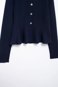 Detail of navy knit cardigan with silver floral buttons and peplum hemline