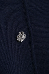 Macro detail of navy knit fabric with a unique irregular silver textured metal button