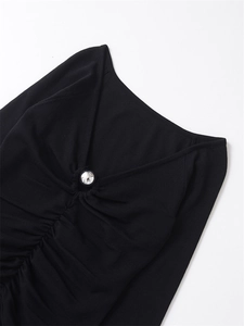 Detail of V-neckline with pleated ruching and silver ball ornament on black knit top