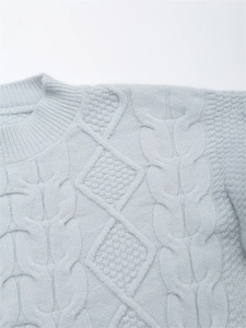 Detail eines hellblauen Strickpullovers mit Zopfmuster und geripptem Rundhalsausschnitt