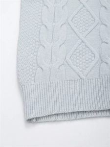 Makroaufnahme von hellblauem Zopfstrickmuster und Rippensaum an einem kuscheligen Pullover