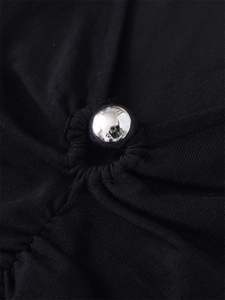 Detail of silver metallic bead on black pleated knit fabric with fine texture