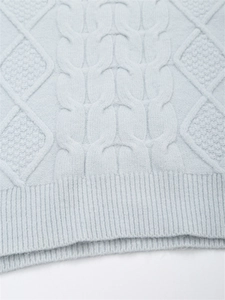 Detailaufnahme von Zopfstrick und Rautenmuster am Saum eines weichen blauen Pullovers