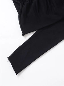 Detail view of soft black knitted fabric texture and minimalist rolled cuff design