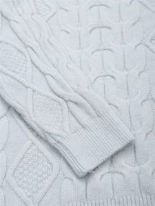 Detailaufnahme von hellblauem Zopfstrickpullover mit weicher Textur und Rippbündchen