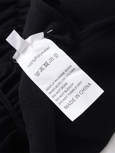 Close-up of 100% polyester fabric care label with washing instructions on black top