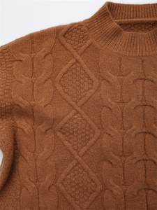 Detail eines warmen karamellfarbenen Strickpullovers mit Zopfmuster und geripptem Kragen