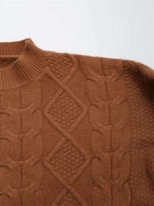 Detail eines karamellbraunen Zopfstrickpullovers mit strukturiertem Rautenmuster