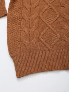 Detailaufnahme des braunen Strickpullovers mit Zopfmuster und Rautenstruktur