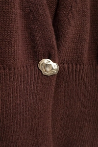 Dettaglio del tessuto a maglia marrone e bottone dorato irregolare sul cardigan moda