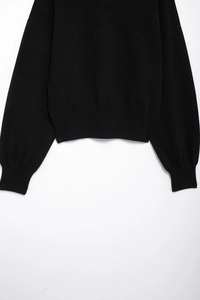 Detail of black knit sweater showing ribbed cuffs and premium textured fabric surface