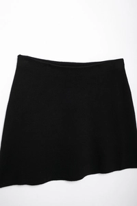 Detailed flat lay of black knit mini skirt featuring fine stitching and elastic waistband
