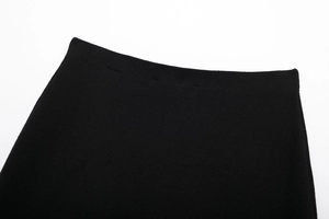 Close-up of the waist area of a black knitted mini skirt with fine texture and stitching
