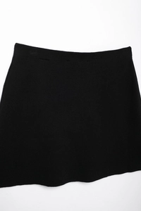 Detailed view of the smooth texture and waistband of a black knitted mini skirt