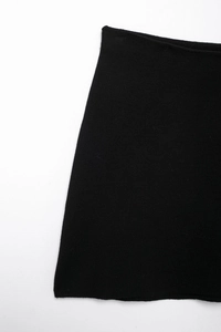 Close-up detail of the smooth black knit fabric and A-line silhouette of the mini skirt