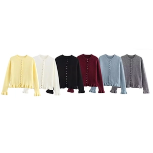 Dettaglio di cardigan in maglia con bottoni di perle e bordi a volant in vari colori