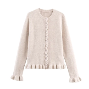Dettaglio dei bordi a volant e piccoli bottoni sul cardigan in maglia bianco crema
